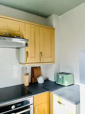 a kitchen with wooden cabinets and a toaster on the counter at Castle Gait Apartment in Paisley