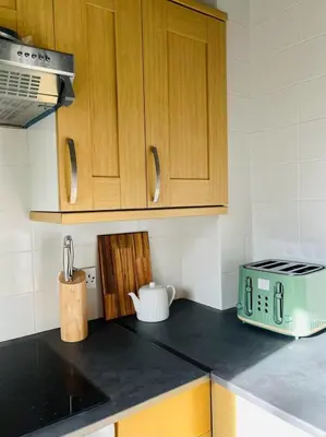 a kitchen with wooden cabinets and a toaster on the counter at Castle Gait Apartment in Paisley