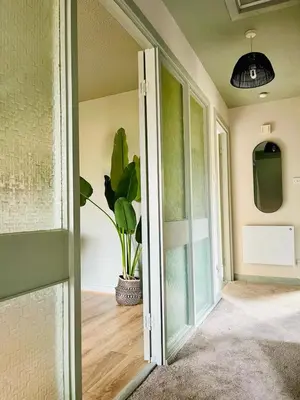 an open door to a room with a potted plant at Castle Gait Apartment in Paisley