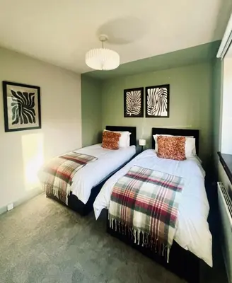 two beds in a bedroom with green walls at Castle Gait Apartment in Paisley