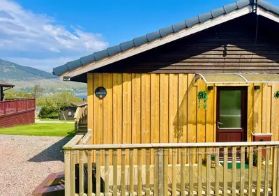 a wooden cabin with a fence in front of it at Harris's Cabin in Hunters Quay
