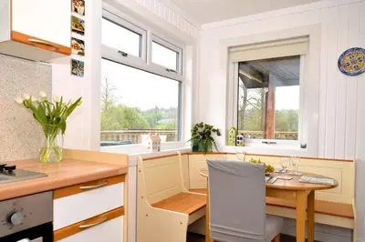 a kitchen with a table and a dining room with a window at Harris's Cabin in Hunters Quay