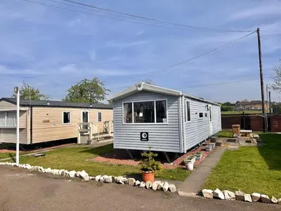 a tiny house is sitting in a yard at 3-Bedroom Swift Caravan - Located in Uddingston, Glasgow at Maryville Caravan Site in Glasgow