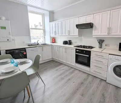 a kitchen with white cabinets and a table and a stove at Campbeltown Central in Campbeltown