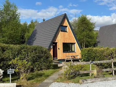 a small wooden house with a black roof at 1 Bedroom Cabin with Mountain & Loch Views - Quiet Location between Glencoe & Ben Nevis in Onich