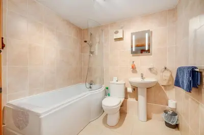 a bathroom with a toilet and a tub and a sink at Courtyard Cottages, Barn Cottage in Wigtown