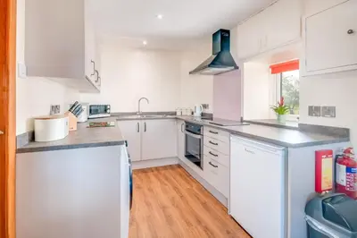 a kitchen with white cabinets and a sink at Courtyard Cottages, Barn Cottage in Wigtown