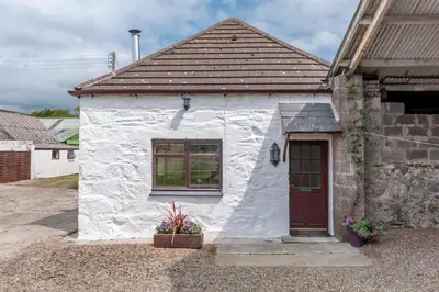 a small white building with a red door at Courtyard Cottages, Barn Cottage in Wigtown