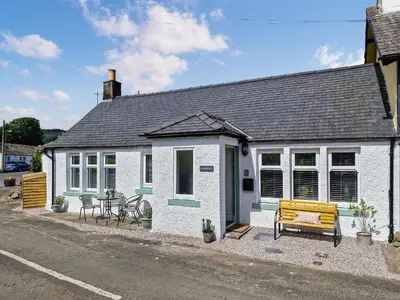 a small white house with a table and a bench at Darroch in Moniaive