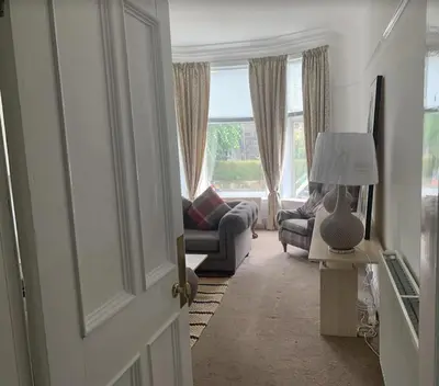 a living room with a couch and a lamp and a door at airport appartment in Paisley