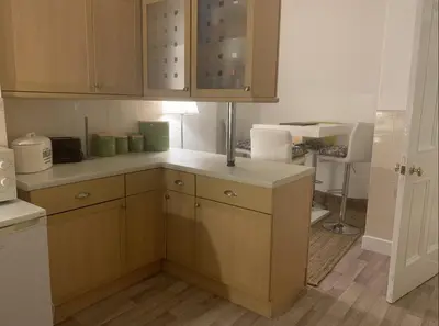 a kitchen with wooden cabinets and a white counter top at airport appartment in Paisley