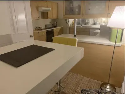 a kitchen with a white counter and a lamp at airport appartment in Paisley