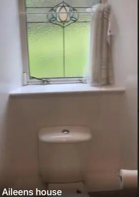 a bathroom with a window and a white toilet at airport appartment in Paisley