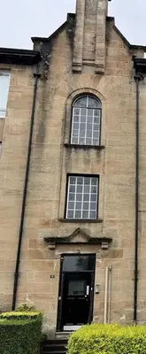 a tall brick building with a window and a door at airport appartment in Paisley