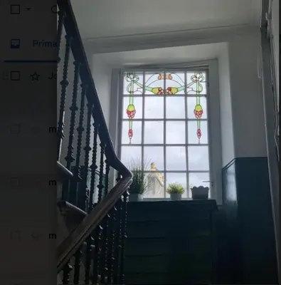 a stairway with a window and a window with a stained glass at airport appartment in Paisley