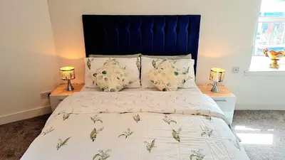 a bedroom with a bed with a blue headboard and two lamps at The Rest in Tarbert