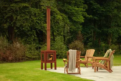 two chairs and a table with a fireplace in a yard at Penicuik Estate in Penicuik