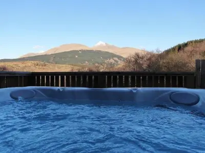 a large hot tub with mountains in the background at Hot tub lodge with stunning view in Taynuilt