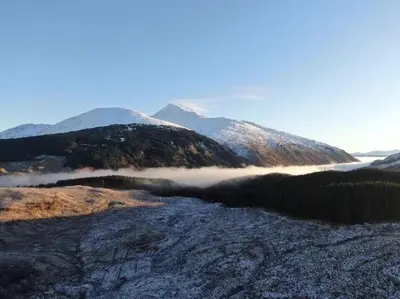 a view of a mountain with fog in a valley at Hot tub lodge with stunning view in Taynuilt