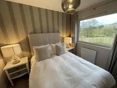 a bedroom with a white bed with a window at Hot tub lodge with stunning view in Taynuilt