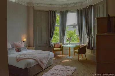 a bedroom with a bed and a window and a table at Hotel Baba in Uddingston
