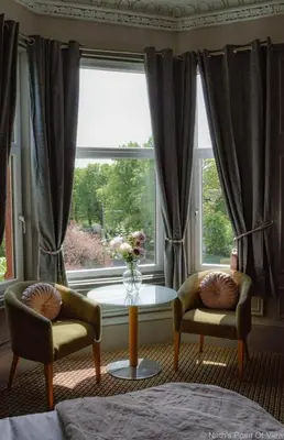 a living room with two chairs and a table and a window at Hotel Baba in Uddingston