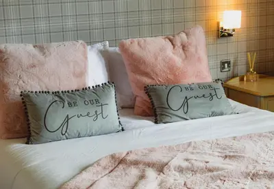 a bed with two pillows on top of it at Hotel Baba in Uddingston