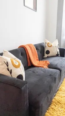 a black couch with an orange blanket on it at 1 BDR Apartment By Caledonia Luxe Stays Short Lets & Serviced Accommodation in Dumbarton