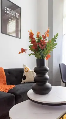 a black vase with flowers on a table in a living room at 1 BDR Apartment By Caledonia Luxe Stays Short Lets & Serviced Accommodation in Dumbarton