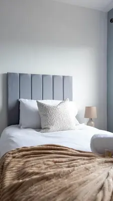 a bedroom with a large white bed with a gray headboard at Blairmuire House in Broxburn