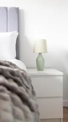 a bed with a nightstand with a lamp on it at Blairmuire House in Broxburn