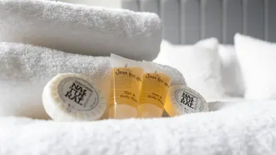 a pile of white towels with a bottle of butter at Blairmuire House in Broxburn