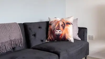 a painting of a cow on a pillow on a couch at Blairmuire House in Broxburn