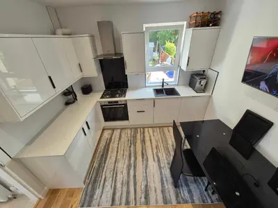 a small kitchen with white cabinets and a table at Lovely house with private parking! Glasgow! in Glasgow