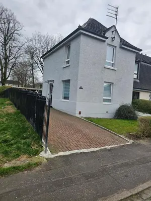 a white house with a fence in front of it at Lovely house with private parking! Glasgow! in Glasgow