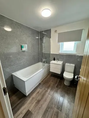 a bathroom with a white tub and a toilet at Inchfad Apartment 2/1 in Bonhill