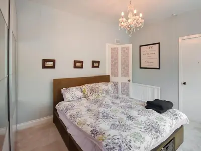 a bedroom with a bed and a chandelier at Nether Auchlinsky Cottage in Glendevon