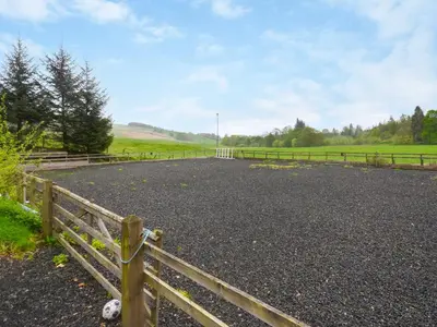 a gravel road in a field with a fence at Nether Auchlinsky Cottage in Glendevon