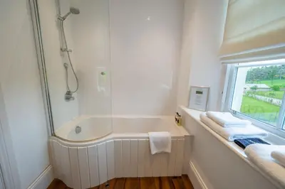 a white bathroom with a tub and a shower at Alexander House 24 - Self Catering in Auchterarder