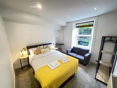 a bedroom with a large bed and a chair at Lovely two bedrooms in Edinburgh