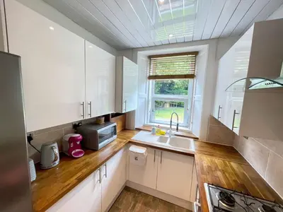 a kitchen with white cabinets and a sink and a window at Lovely two bedrooms in Edinburgh