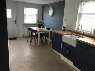 a kitchen with blue cabinets and a table with chairs at Caerlaverock Cottage in Prestwick