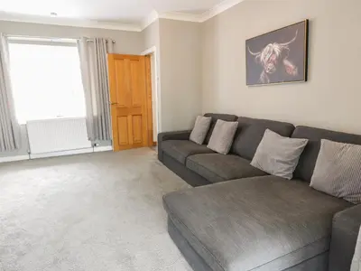 a living room with a gray couch and a window at Largieholm in Mauchline