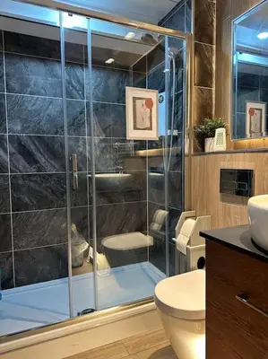 a bathroom with a glass shower with a toilet and a sink at Top Floor of the building, spectacular views! in Glasgow