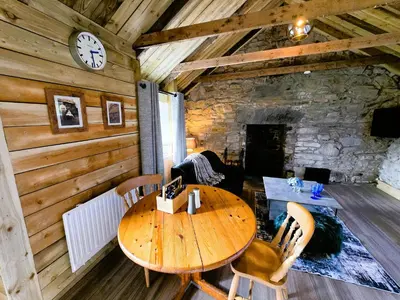 a wooden table and chairs in a room with a stone wall at Ard Veich Estate - Panoramic Highland Sea Views with private beach and woodland in Port Appin