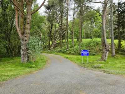 a winding road with a blue sign in the middle at Ard Veich Estate - Panoramic Highland Sea Views with private beach and woodland in Port Appin