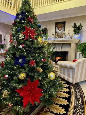 a christmas tree in a living room with a fireplace at FINN VILLAGE - Loch Lomond Villa - THE JUNGLE ROOM with a PRIVATE HOT TUB in Drymen
