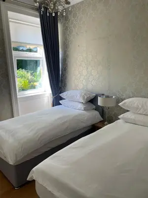 two beds in a bedroom with a window at Inverbeg Cottage in Rothesay