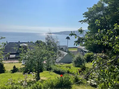 a view of a garden with the ocean in the background at Inverbeg Cottage in Rothesay