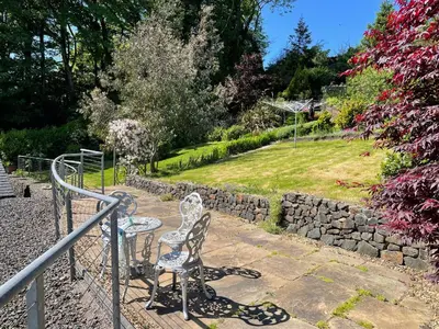 a chair sitting on a stairway next to a stone wall at Inverbeg Cottage in Rothesay